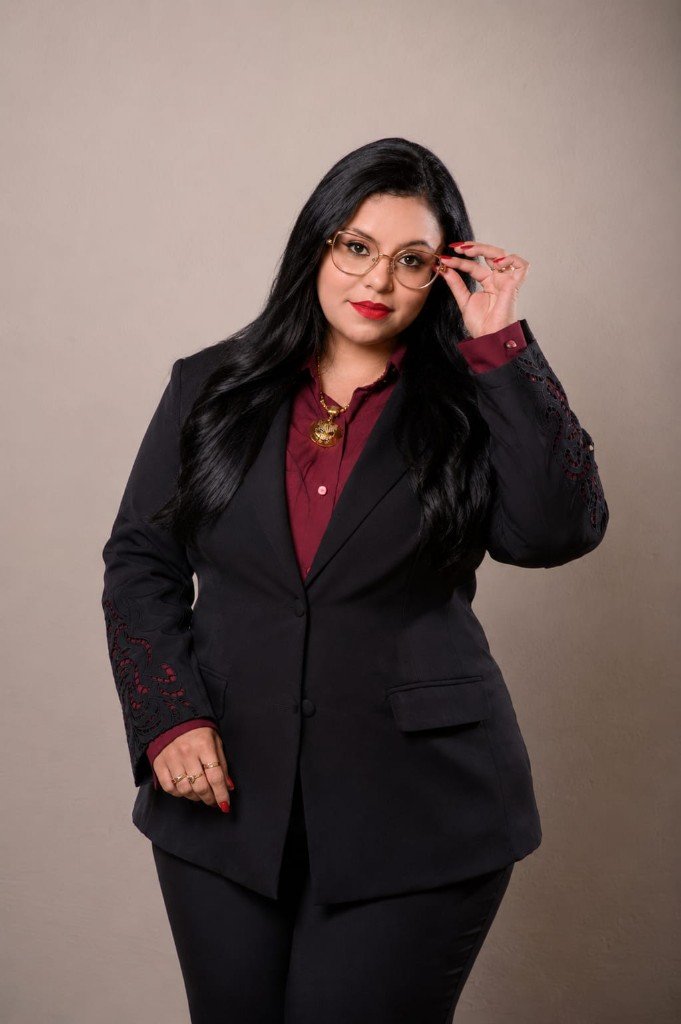 Dra. Karen Lorrayne ajustando os óculos, em traje formal preto e vinho